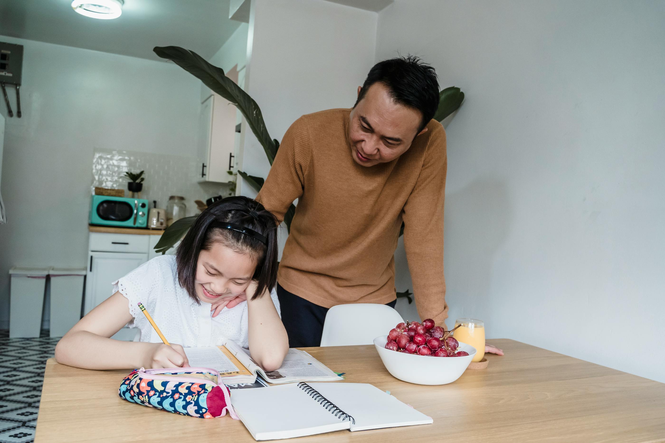 An adult warmly helping a child with schoolwork at a table