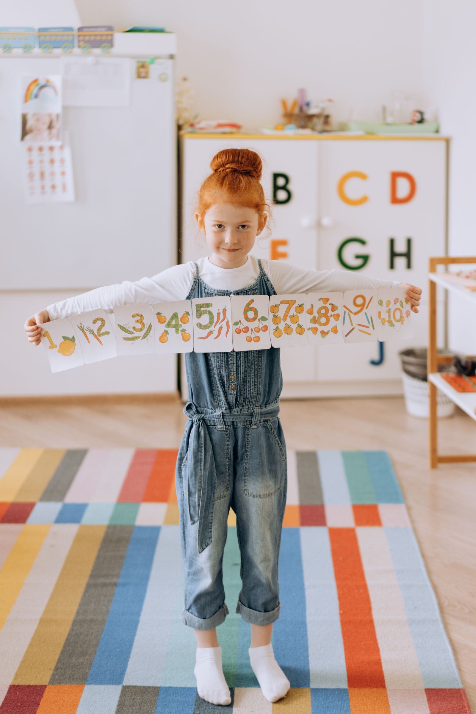 A child holding number cards in a bright classroom