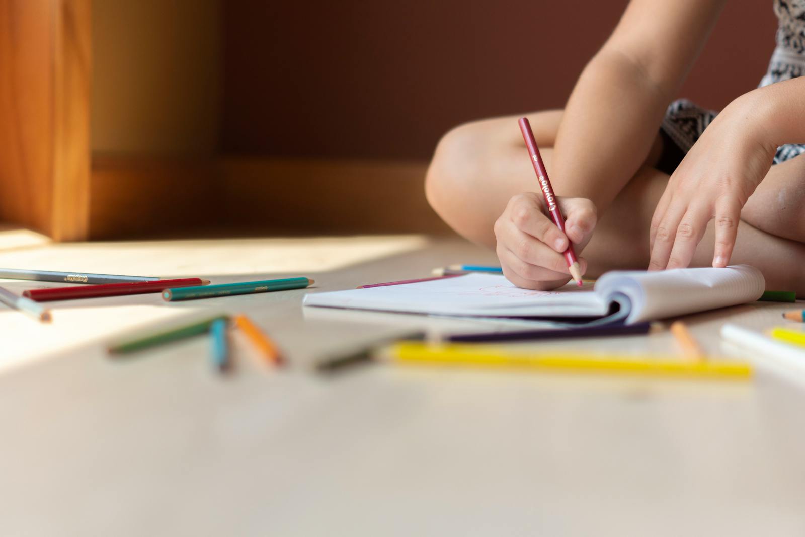 Close-up of a child writing with a colored pencil