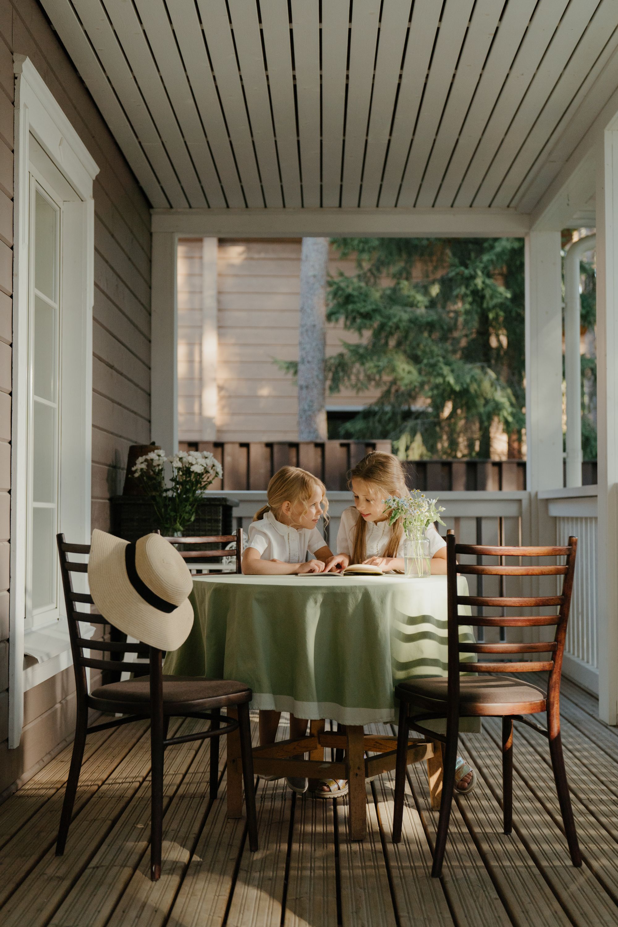 Two children reading a book together at a table in warm afternoon light